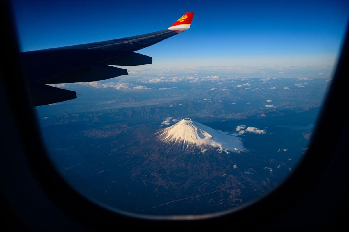 Stunning aerial view of Mount Fuji from an airplane window, capturing the iconic snow-capped volcano.