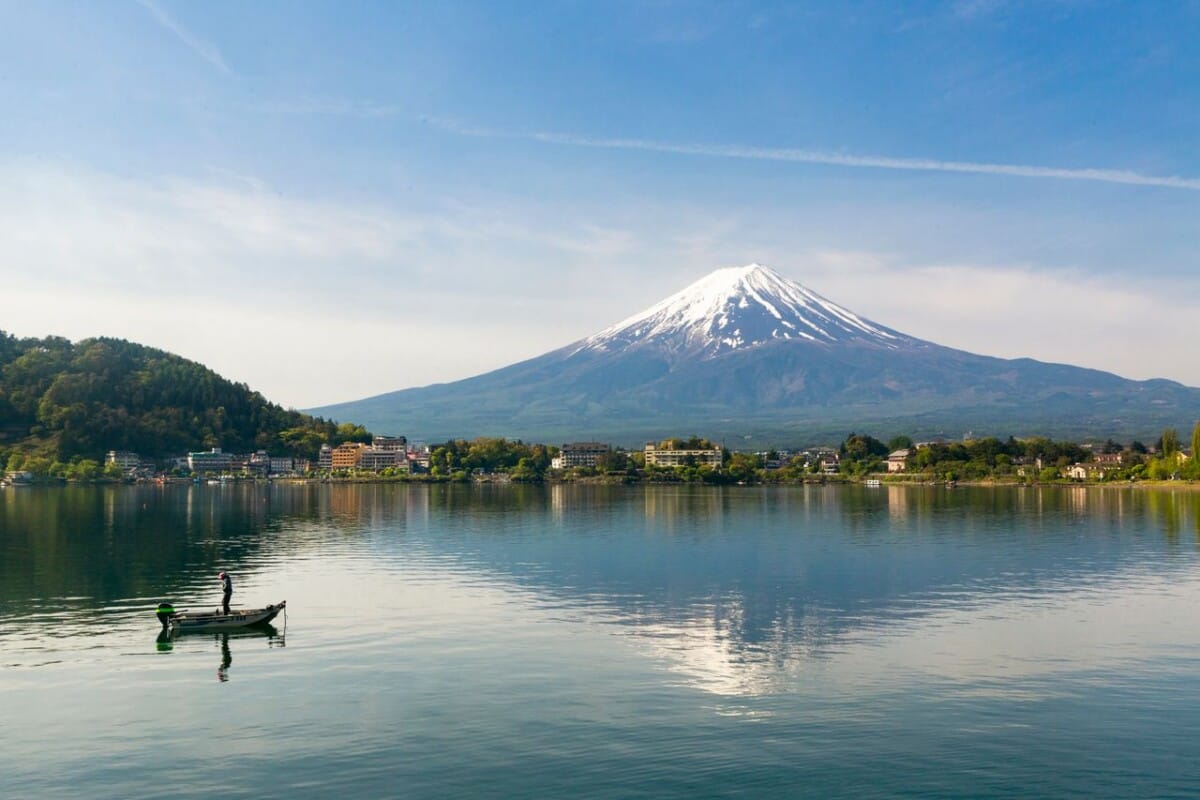 A serene view of Mount Fuji with a fishing boat on Lake Kawaguchi, Japan.